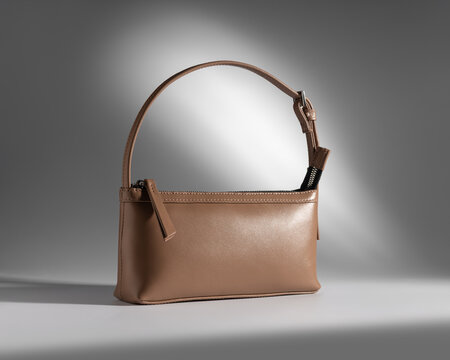 Elegant light brown leather baguette purse with shoulder strap in spotlight