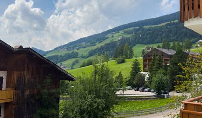 Obraz premium traditional alpine village, featuring rustic wooden buildings and lush green mountain slopes under a bright blue sky