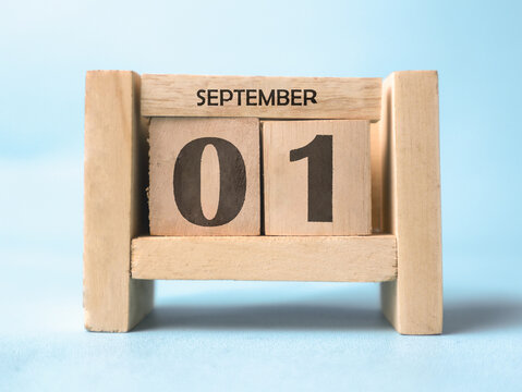 A wooden block calendar for September 1st on a light blue background.