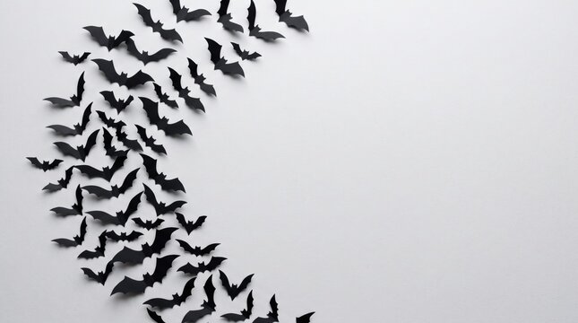 Black paper bats arranged in a curved formation on a white background, creating a minimalist and spooky Halloween-themed design.