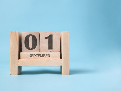 A wooden block calendar for September 1st on a light blue background.