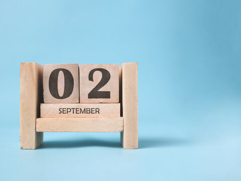A wooden block calendar for September 2nd on a light blue background.