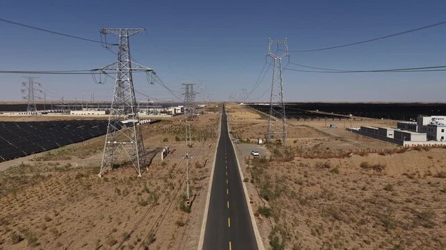 High-voltage Power Transmission Towers and Solar Farm Along Asphalt Road in Gobi Desert, Northwest China