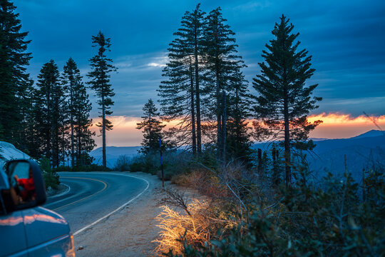 Road trip adventure with car on a winding mountain highway at twilight sunset