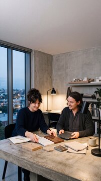 Two interior designers sitting at a concrete table reviewing wood, marble, and stone material samples in a modern architecture studio