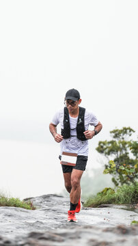 Trail runner navigating a wet mountain path in rainy weather with dramatic copy space