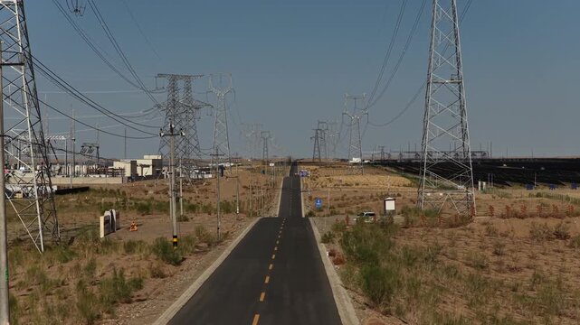 High-voltage Power Transmission Towers and Solar Farm Along Asphalt Road in Gobi Desert, Northwest China