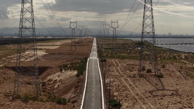 High-voltage Power Transmission Towers and Solar Farm Along Asphalt Road in Gobi Desert, Northwest China