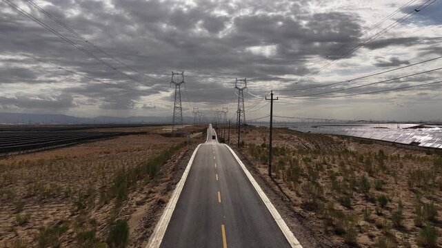 High-voltage Power Transmission Towers and Solar Farm Along Asphalt Road in Gobi Desert, Northwest China