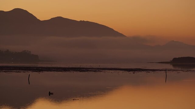 4K 30fps footage of a tranquil sunrise over the Kleinrivier Estuary and Kleinrivier Mountains near Hermanus on South Africa&rsquo;s Whale Coast. Dawn light reflects on calm waters in the Overberg region.