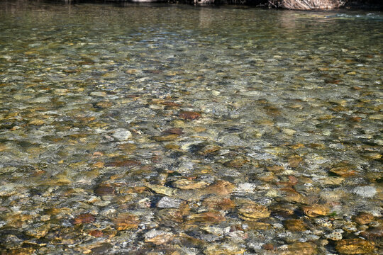 Clear mountain river with visible stones and gravel on the riverbed. Crystal clear water of the Neretva river in Bosnia and Herzegovina. Flowing mountain riverbed.