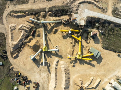 Aerial view of a sand quarry and gravel pit. Open-pit mining for construction materials with heavy machinery, conveyor belts, and processing equipment. Industrial background from above.