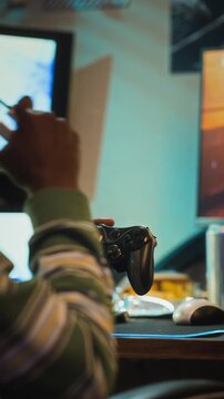 Vertical video of African American teenager playing video games with controller and smoking vape. Ideal for content about gaming addiction, smoking habit, digital wellness, and youth lifestyle
