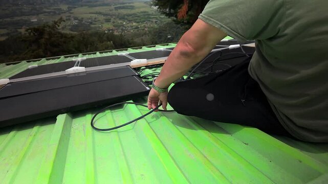 worker connecting solar panel cables on green roof in colombia
