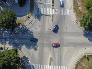 Vehicles navigating through an urban intersection from an aerial drone view. Aerial drone shot of cars driving through a city intersection. © Ajdin Kamber