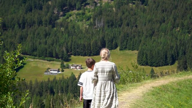 A mother and son are walking along a path in the mountains