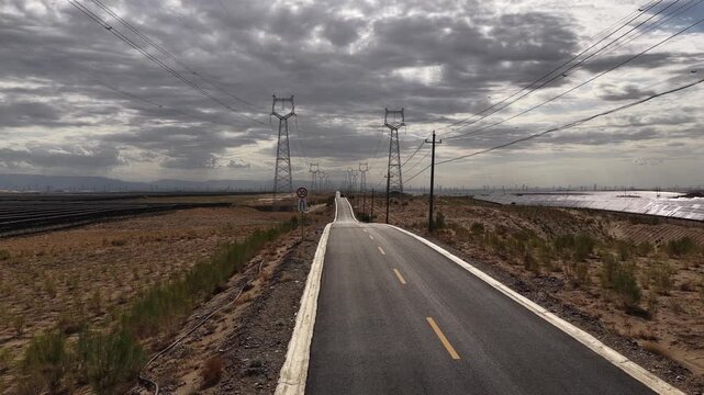 High-voltage Power Transmission Towers and Solar Farm Along Asphalt Road in Gobi Desert, Northwest China
