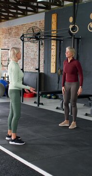 Vertical video: Female trainer cueing balance, guiding client through shoulder drills at gym rings