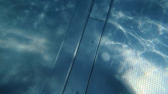 Swimming pool bottom with sunlight rippling across textured surface