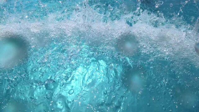 Underwater bubbles rising and swirling beneath turquoise water surface