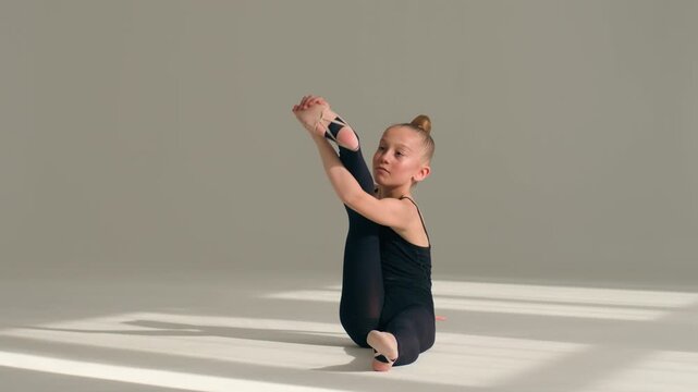 Caucasian little girl gymnast ballerina dancer acrobat stretching back bend exercise in ballet studio flexible child athlete schoolgirl training gymnastics dance school body workout competition indoor