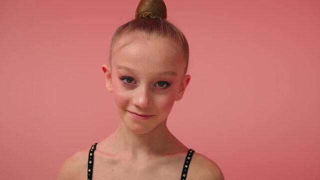 Smiling Caucasian little girl gymnast dancer ballerina child looking camera inside pink studio happy female kid athlete spinning sport exercise artistic daughter schoolgirl acrobat gymnastics ribbon