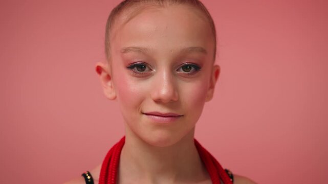 Close up portrait little girl gymnast smiling happy Caucasian child schoolgirl dancer ballerina athlete with makeup pink background cute female kid looking camera sport childhood artistic gymnastics