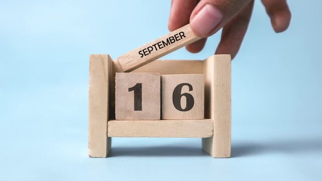 A woman&rsquo;s hand is holding a wooden block of the dates in the month of September. Month of September wooden block calendar timelapse.