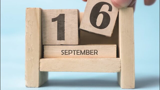 A woman&rsquo;s hand is holding a wooden block of the month of September. Month of September wooden block calendar timelapse.