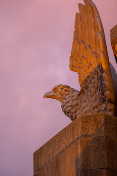 Golden Eagle Stone Sculpture Against Vibrant Sunset Sky