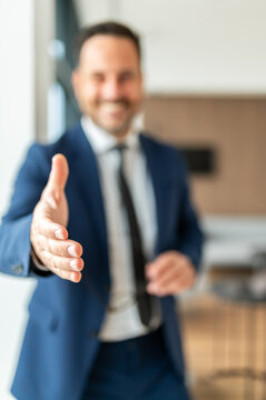 Professional businessman offering a hand for a handshake, conveying a sense of welcome, establishing a new partnership, or sealing a successful business agreement