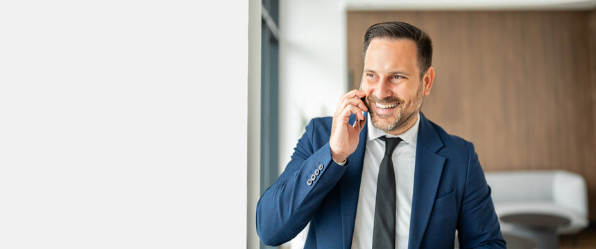 Smiling professional businessman having a mobile phone conversation. Connecting with clients. Discussing finances. Managing investments