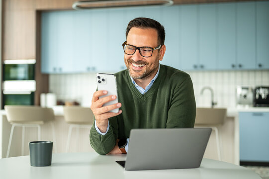 Professional man smiling while using a mobile phone, engaging in online communication for business, finance, or legal services from a remote workspace