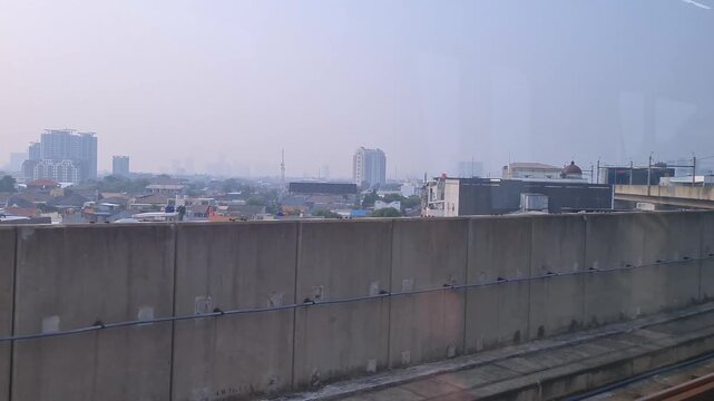 A view from inside Jakarta MRT train as it leaving a station platform showcasing Jakarta Skyline and suburbs in the city center.