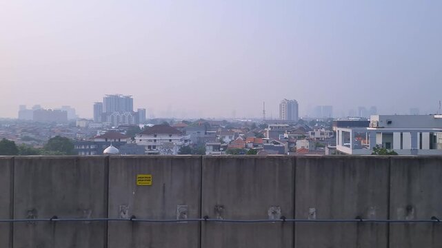 A view from inside Jakarta MRT train as it leaving a station platform showcasing Jakarta Skyline and suburbs in the city center.