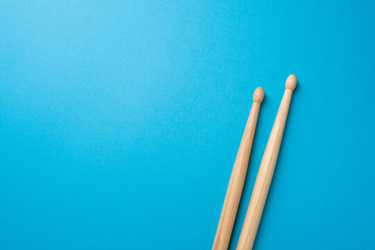 Pair of drumsticks placed on vibrant blue background