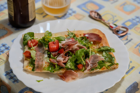 Homemade white pizza with arugula, prosciutto, and cherry tomatoes
