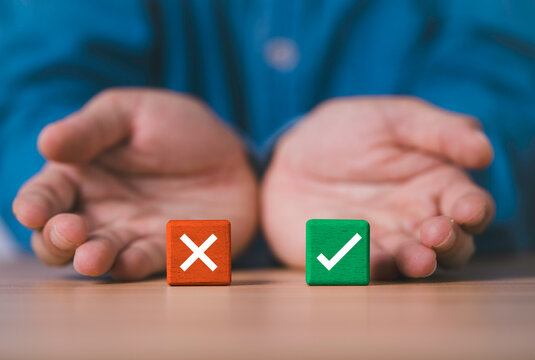 Hands presenting red cross and green check blocks symbolize right or wrong choice of decision making with approval and rejection evaluation yes or no of business judgment concept.