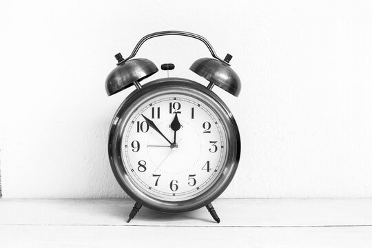 Old vintage alarm clock on white background, timeline and deadline background idea, black and white filter effect