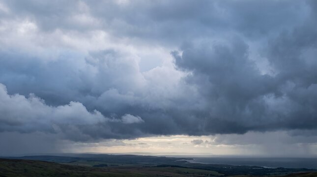Vast storm clouds gathering on horizon over rolling green hills with dramatic sky and distant rain showers