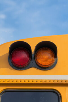 School bus lights against clear blue sky showing red and amber signals for safety and awareness. School bus lights are crucial for student safety during pick-up and drop-off times.