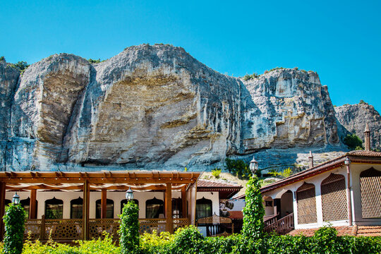 Tourist cabins against the backdrop of an overhanging cliff on a clear, sunny day. Nature, landscape, world tourism.