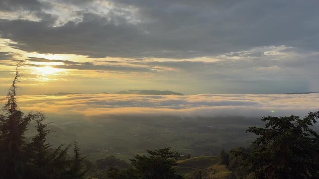 sunrise over mountains and valley covered by thick fog and golden clouds