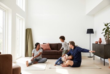 Fototapeta premium Diverse family with two children exercising together on mats in a bright living room at home