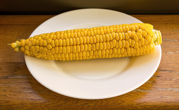 Baked fresh organic yellow corn on ceramic plate at home table interior
