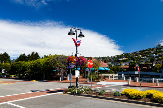 Waterfront street scene in Belvedere, California with stop sign, flag and floral baskets