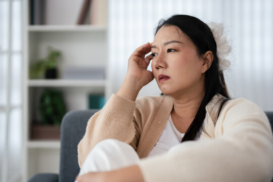 Woman sitting on sofa pensive look depression.