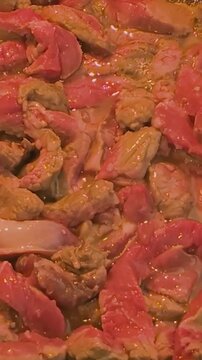 Frying pieces of meat in a pan on the stove for cooking at home during dinner time