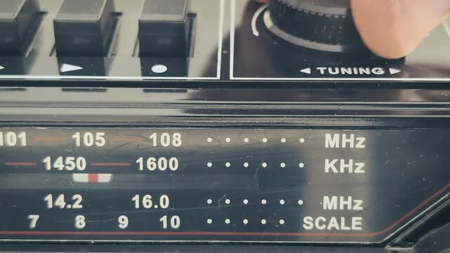 Searching for radio tuning on an old radio recorder in a quiet room during afternoon light