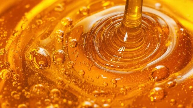Close up of golden honey pouring with bubbles and rich texture in natural light